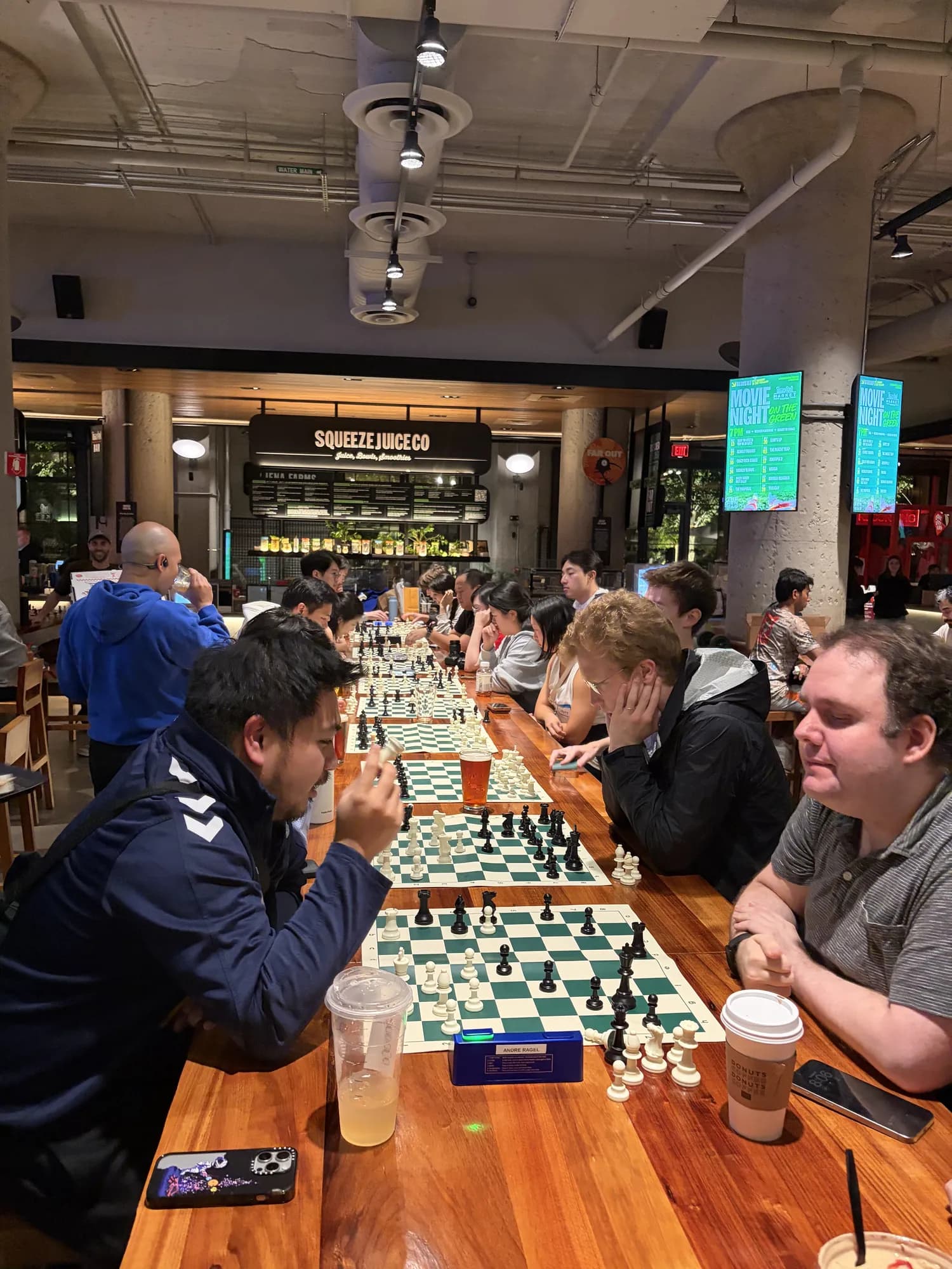Two players face off across a board as others play down the table